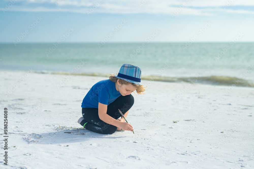 Summer child face. Cute kid kid drawing a on sand enjoying summer sea and dreaming. Funny little boy play on summer beach. Happy boy enjoys life on summer beach.