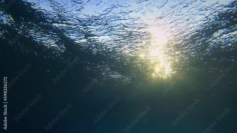 Flickering sun rays passing through ripples on the surface of the water ...
