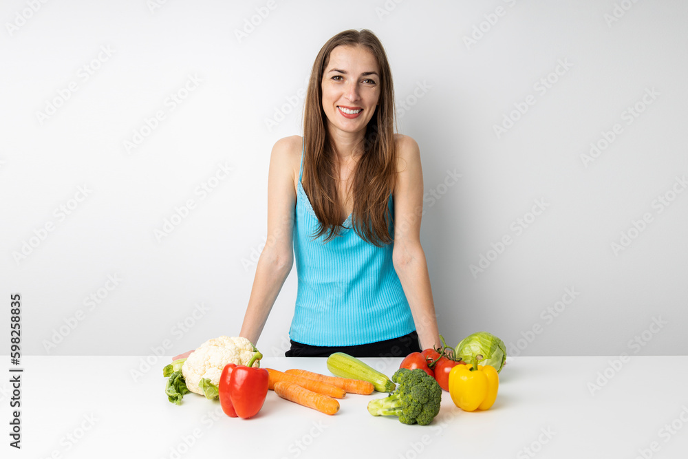 Smiling young woman in the kitchen fresh vegetables lie on the table Smiling young woman in the kitchen fresh vegetables lie on the table