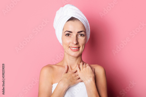 skin care. Smiling girl with a towel on her head on a pink background