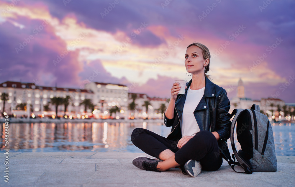 Enjoying drink. Young woman drinking coffee on sea promenade.