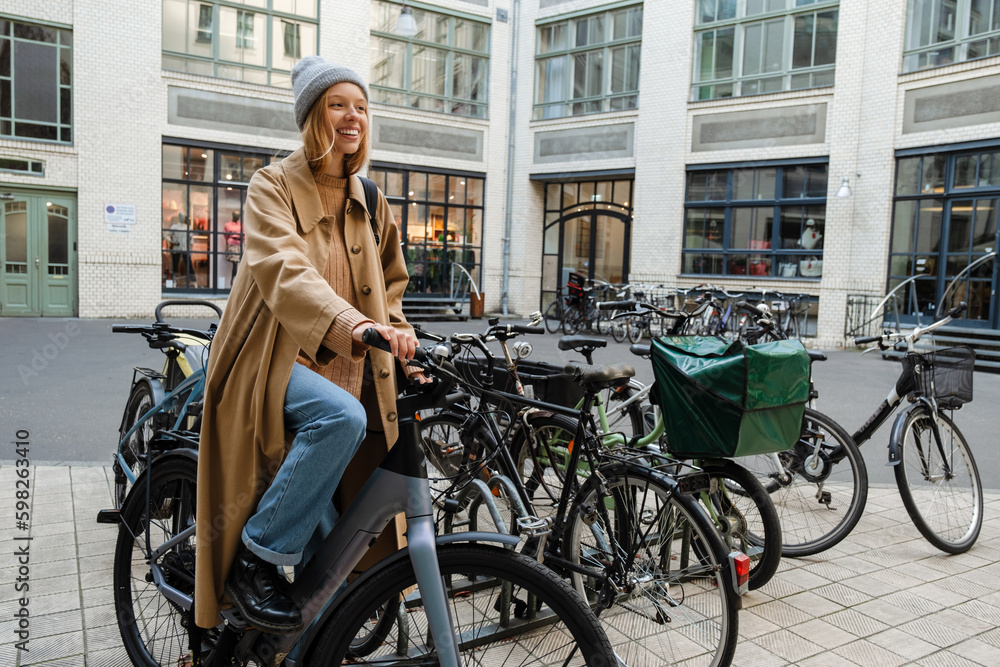 Cheery blonde woman standing with bike outdoors