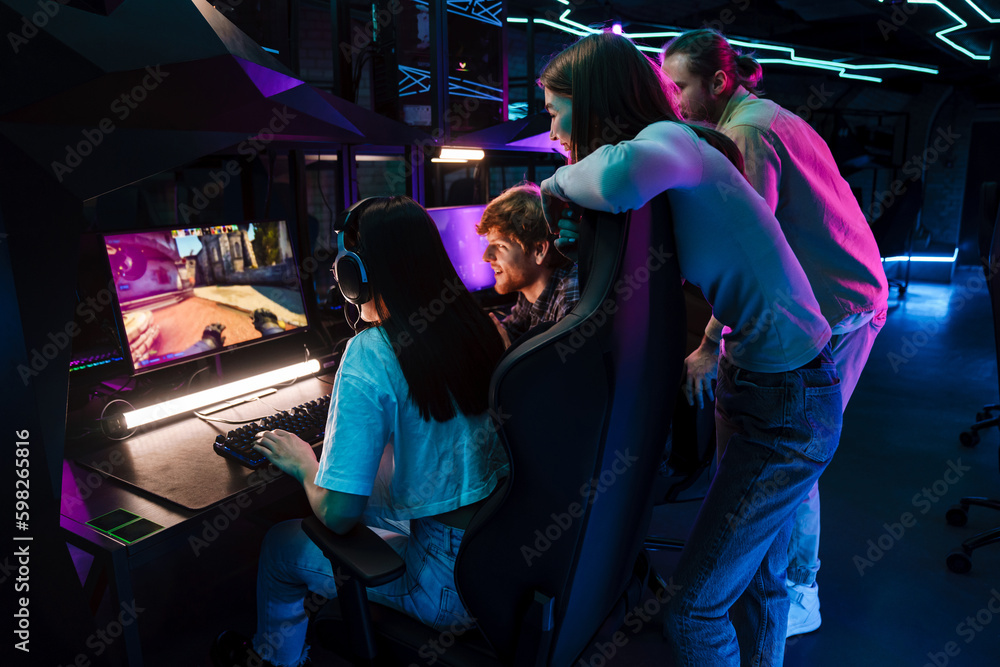 Group of people watching their friend playing video game and assisting her in cybersport club Group of people watching their friend playing video game and assisting her in cybersport club