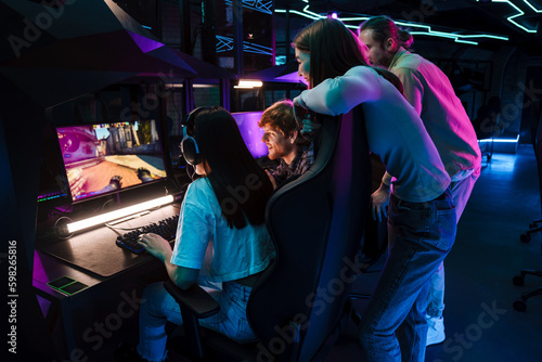 Canvas Print Group of people watching their friend playing video game and assisting her in cy