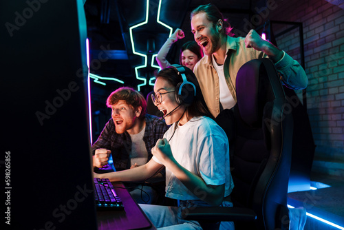 Canvas Print Group of friends celebrating victory of asian girl in video game while standing