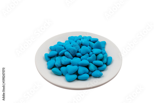 White plate with blue heart-shaped candies (close-up) isolated on white background