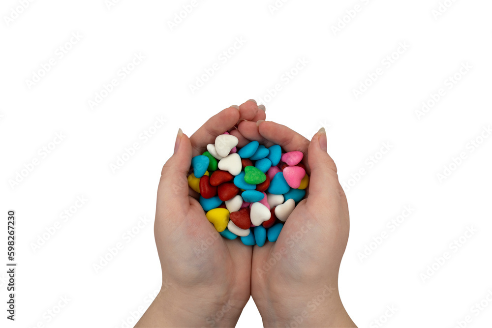A handful of multi-colored heart-shaped sweets in hands on a transparent background