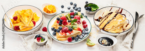 Sweet crepes assortment with berries chocolate on gray background. Homemade food concept. Top view, flat lay