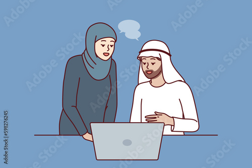 Office workers in Arabic clothing discussing business presentation from laptop. Arabic man and woman work together in corporation in dubai or emirates and conduct business negotiations Generative AI