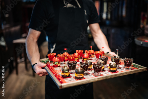 Drunken checkers. waiter hold checkers with shot alcoholic drinks and mini burgers photo