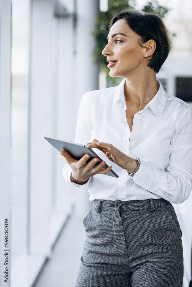 Young business woman holding tablet and smiling at the office Young business woman holding tablet and smiling at the office