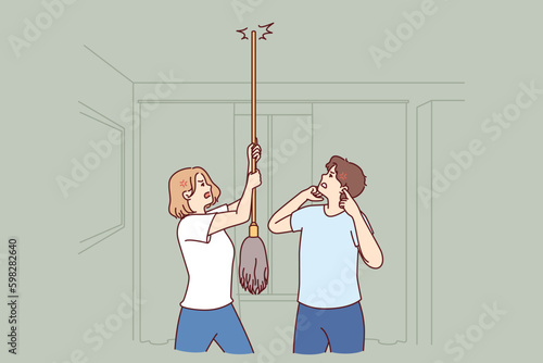Young couple bangs on ceiling with mop urging neighbors to stop party or turn off loud music. Angry men and women use mop suffer from noisy neighbors not respecting rules of living Generative AI