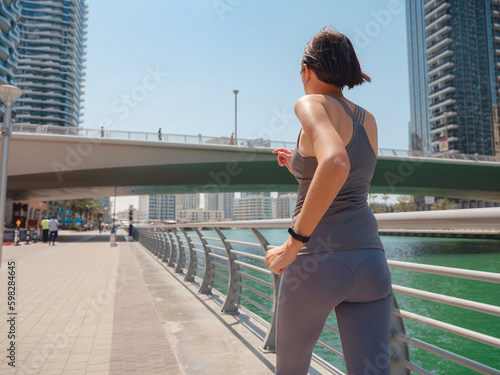 City Running - asian woman runner , Dubai marina urban scene in background. Female athlete, fitness athlete jogging training, living healthy lifestyle. back view © YURII Seleznov