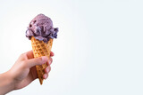 Hand holding delicious blueberry ice cream in a crispy waffle cone with copy space. Created with Generative AI Technology
