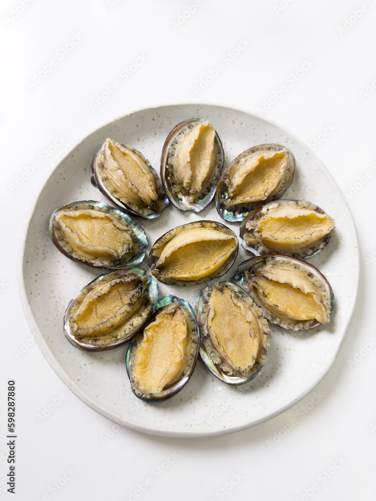 Delicious raw abalone in a plate on white table background. Delicious raw abalone in a plate on white table background.
