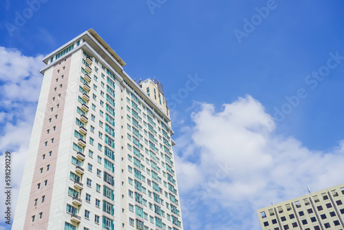 High-rise building photographed from below in the morning with clouds and blue sky background.