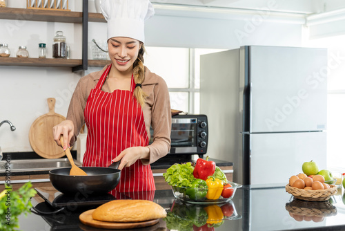 Beautiful asian young female chef preparing healthy food in kitchen