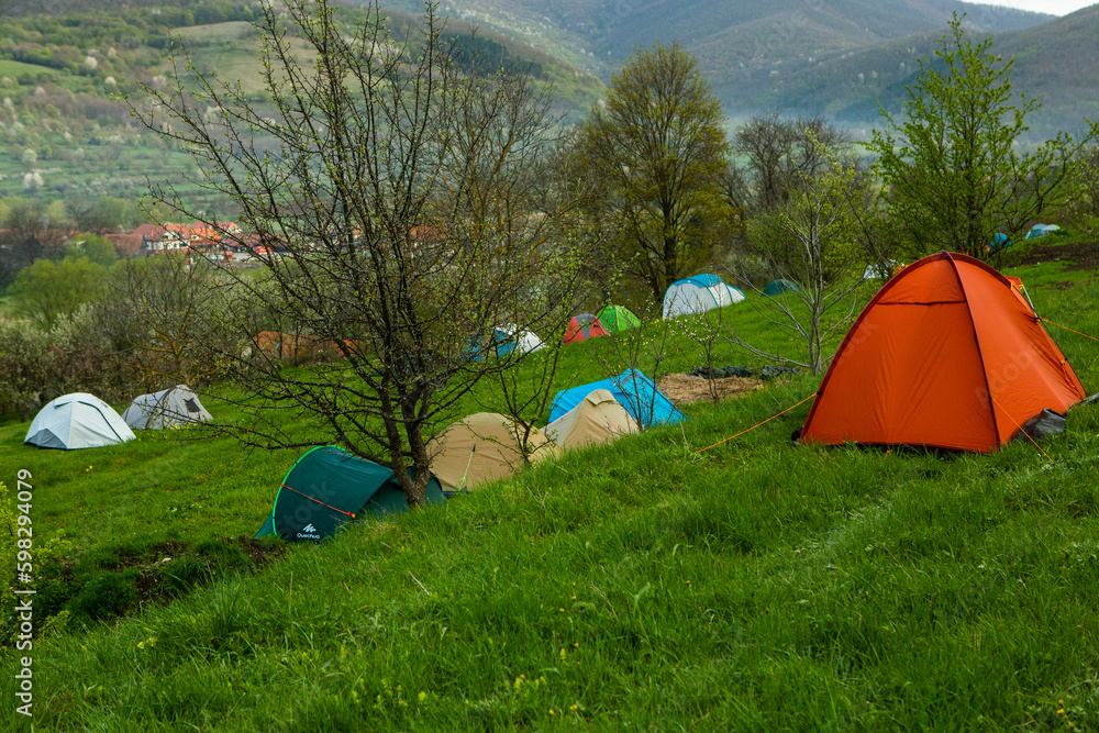 Camping tents on a green meadow in the mountains in spring. Rest with the tent in nature