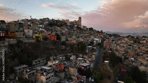 Ascending aerial view of poor homes and streets in the mountains of Naucalpan, sunset in Mexico photo