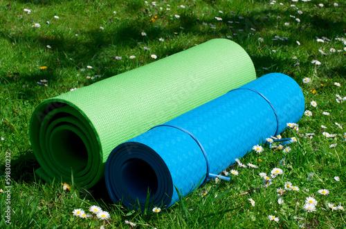 Two yoga mats on the grass in the garden. Green and blue yoga mats