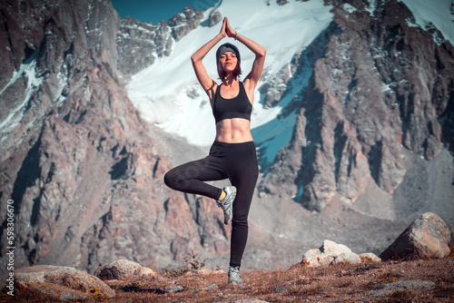 Girl doing exercises on the background of snowy mountains. © Zhanna