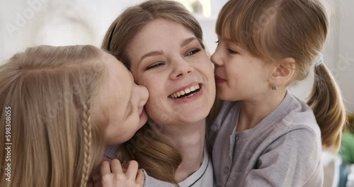 Slow motion shot of caucasian beautiful woman laughing cheerfully while cute daughters embracing and kissing her on cheeks at home Generative AI