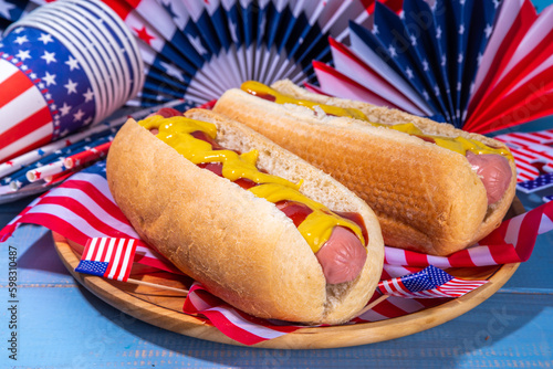 USA Patriotic picnic holiday hot dogs. American patriotic hot dog on wooden board plate, with USA flag. Celebrating Independence day on 4th July, Memorial or Veteran Day