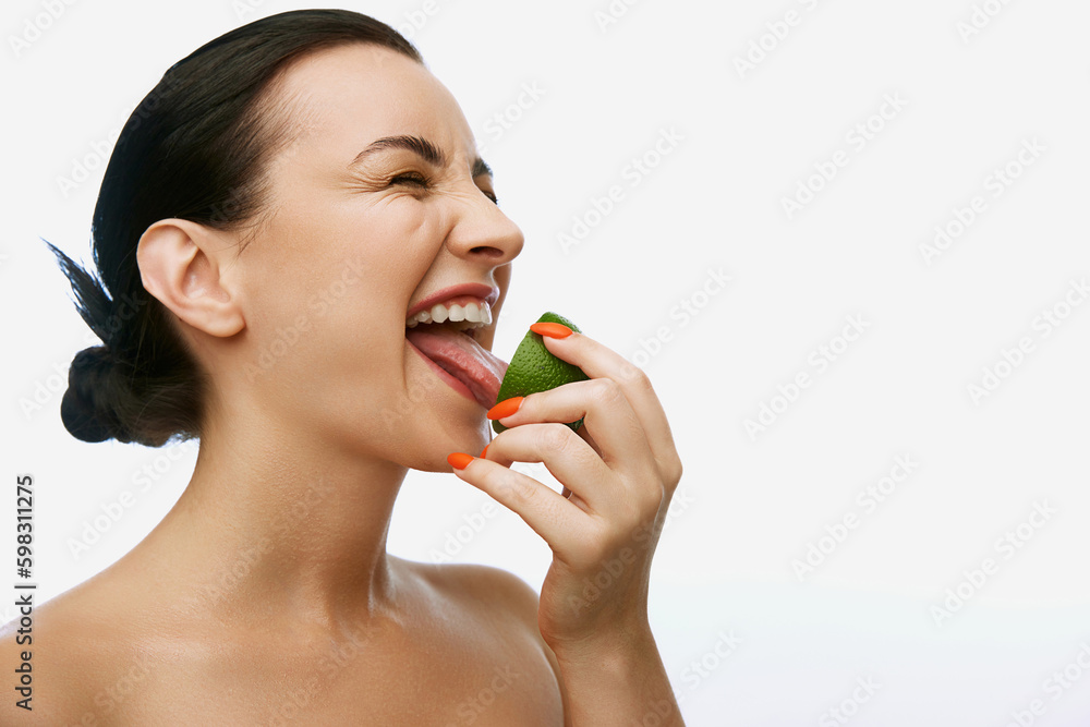 Portrait with funny, young, adorable woman with bare shoulders licking sour lime piece over white studio background. Cosmetology Portrait with funny, young, adorable woman with bare shoulders licking sour lime piece over white studio background. Cosmetology