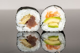 Two sushi rolls with salmon, tuna and avocado. Sushi with reflection. Traditional japanese food
