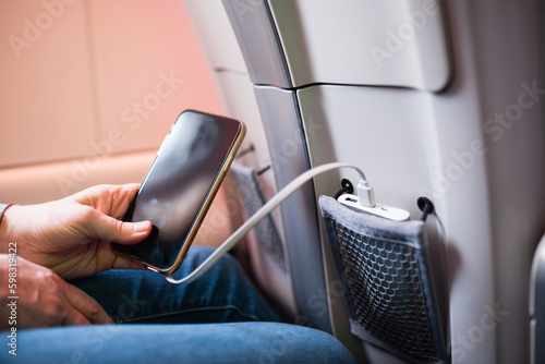 Paris, France - December 28, 2022: Convenient pocket in the airplane seat for storing your phone and portable charger - recharging on the go while traveling