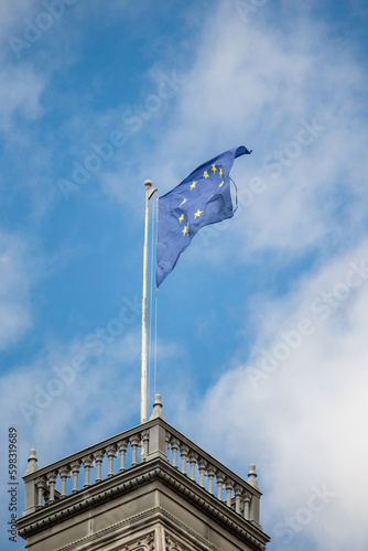Vienna, Austria - April 01, 2023: The flag of the European Union against the blue peaceful sky on the roof of the medieval town hall - a symbol of European values