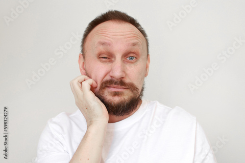 shot mans hand is unrestrained scratching unshaven chin. Overgrown unkempt male in white t shirt with thick beard and mustache face. Beauty salon concept, barbershop
