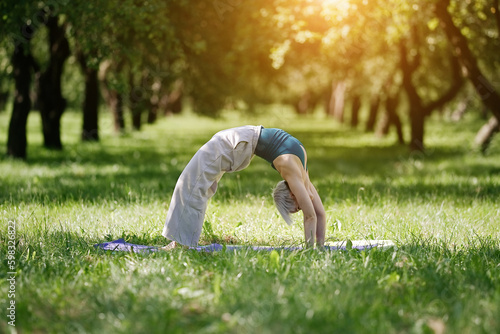 Young woman doing yoga exercise outdoor in the park, sport yoga concept