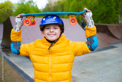 Fototapeta portrait of a smiling schoolboy in a safety helmet with a bright blue skateboard