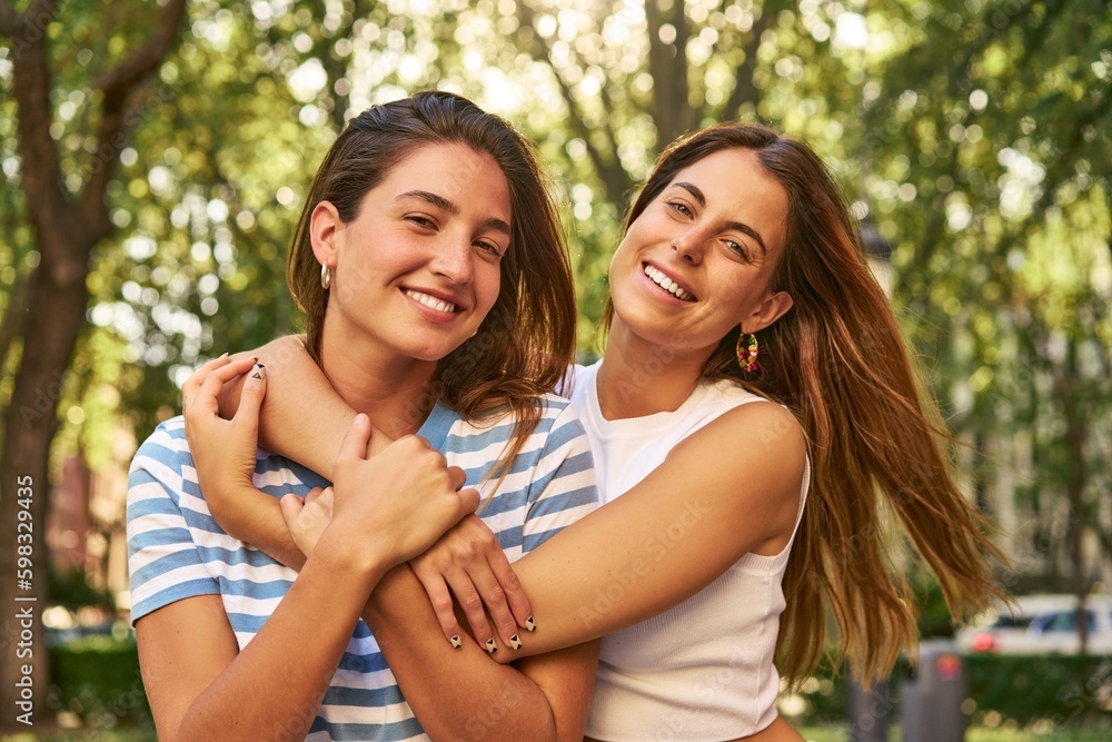 Two friends embrace and smile in a park. Two friends embrace and smile in a park.