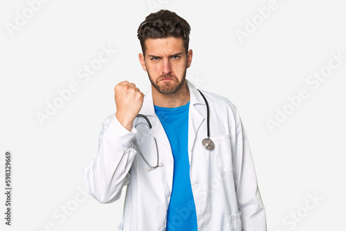 Young doctor man showing fist to camera, aggressive facial expression.