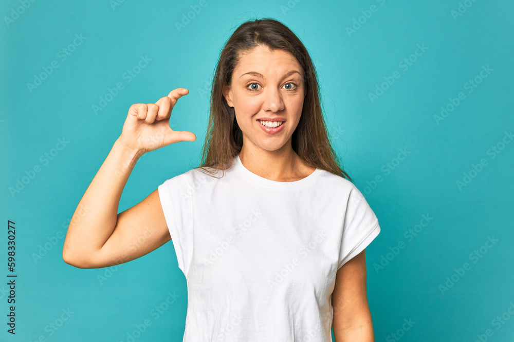 A young caucasian woman isolated holding something little with forefingers, smiling and confident. A young caucasian woman isolated holding something little with forefingers, smiling and confident.