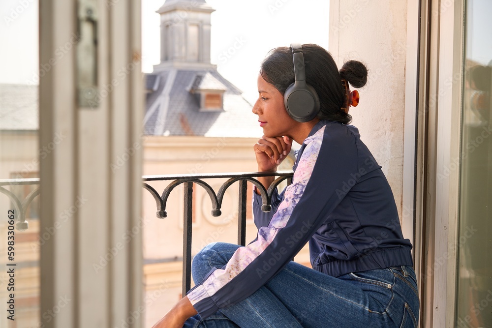 Stylish young Indian woman enjoying music on headphones.