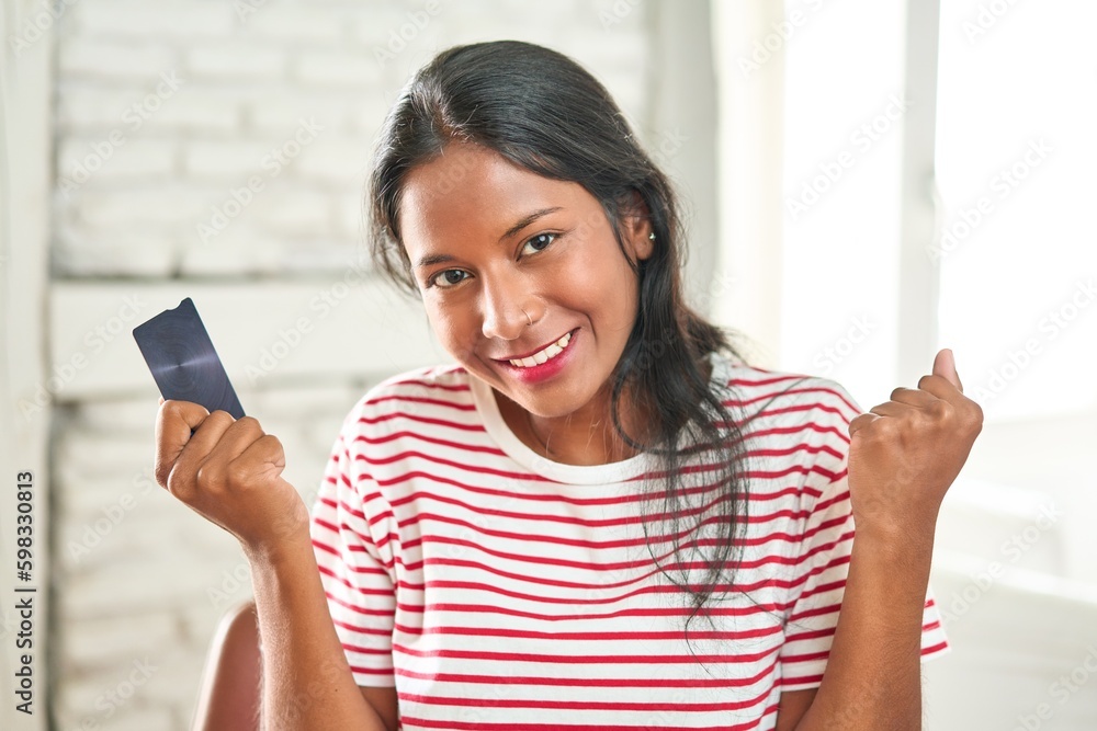 Excited young Indian woman celebrating with credit card in hand. Excited young Indian woman celebrating with credit card in hand.