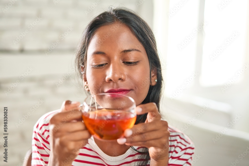 Joyful young Indian woman enjoying a hot cup of tea. Joyful young Indian woman enjoying a hot cup of tea.