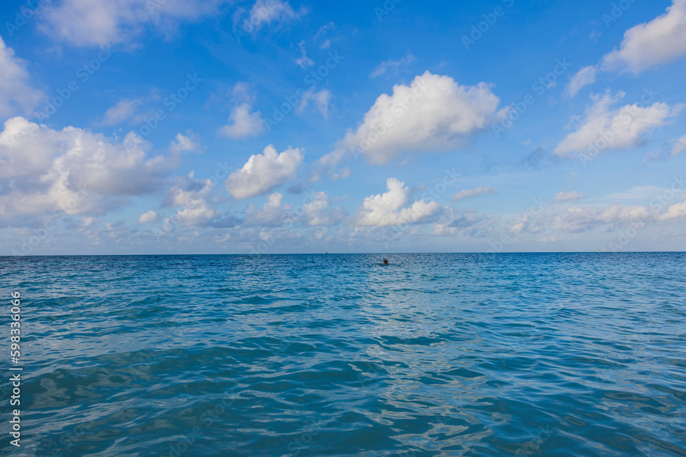 Obraz premium Beautiful view of blue water of Atlantic Ocean on island of Aruba on background of sky with white clouds.