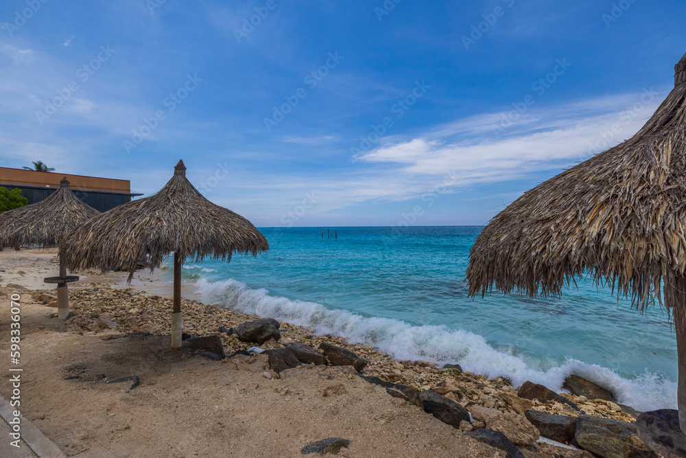Beautiful view of sun beds and umbrellas on beach Atlantic ocean of hotel. Aruba.