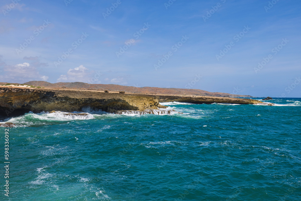 Beautiful view of rocky coast washed by Atlantic Ocean waves. Aruba. 