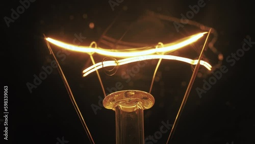 Tungsten light bulb flickering over black background.
