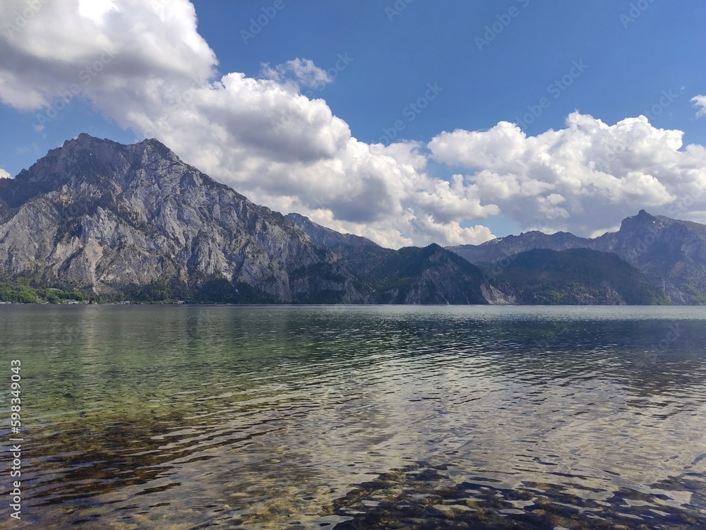 Lake and mountains. Mountain lake in Austria. Crystal clean water. Summer day, blue sky. Alps. Lake coastline. Rocks. Relaxing view.