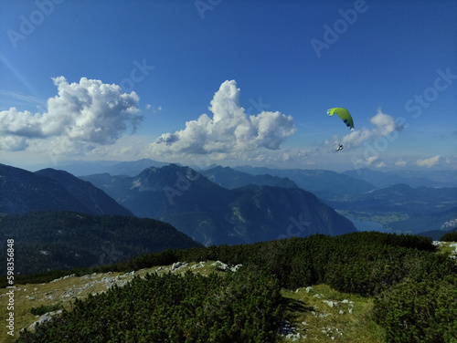Pragliding in the mountains. A view on a mountains and Halstattersee from the top. Blue sky and white clouds. Summer in mountains. Paragliding in Alps. Flight. Extreme.