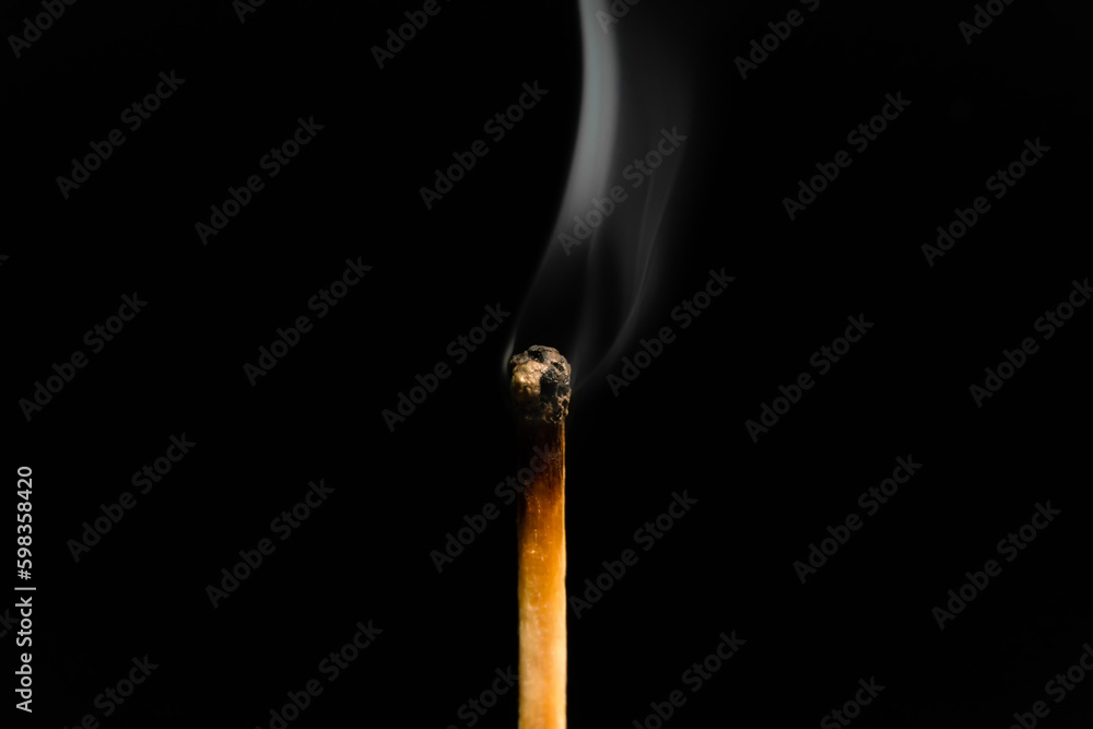 A lit match with smoke on a black background, macro photography. An extinguished match with smoke.