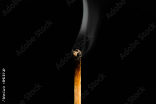 A lit match with smoke on a black background, macro photography. An extinguished match with smoke.