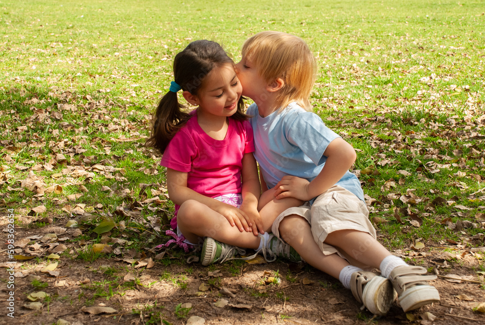 Little childrens sit on a grass in the park Little childrens sit on a grass in the park