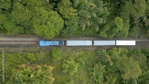 A historic train riding threw the jungle of Costa Rica, surrounded by rain forest, painted in Costa Rican flag colors (Aerial view, drone, 4K)